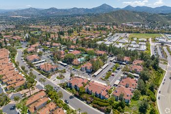 An aerial view of a neighborhood with houses and trees and mountains in the background